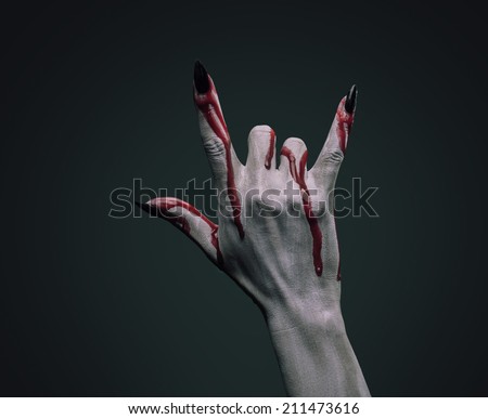 Vampire hand in blood on dark background, rock hand sign