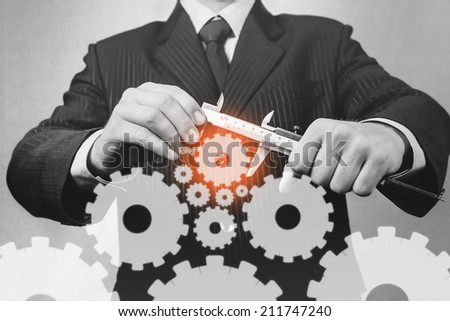 Unrecognizable businessman holds calipers with cogwheels, concept of business creation, monochrome image