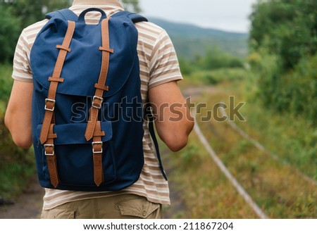 Unrecognizable hiker man with backpack going on path in summer, rear view