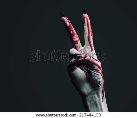 Vampire hand in blood on dark background, peace hand sign. Halloween or horror theme