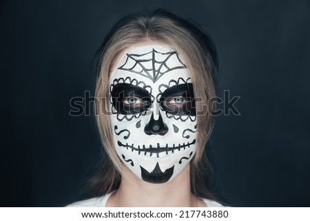 Portrait of smiling young woman with sugar skull makeup. Halloween face art