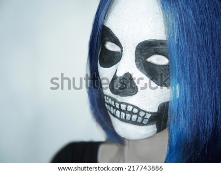 Portrait of young woman with skull makeup and white eyes. Space for text in left part of image. Halloween or horror theme
