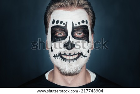 Portrait of smiling young man with sugar skull makeup. Halloween face art