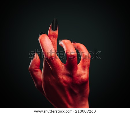 Red demon hand with gesture cross fingers on dark background. Halloween or horror theme