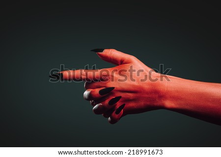 Red demon hand with gesture shoot on dark background. Halloween or horror theme