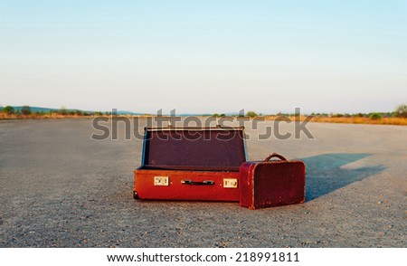 Vintage open suitcase and small bag on road, space for text in upper part of image. Travel theme