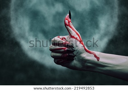 Vampire hand in blood with thumb up gesture on background of full moon. Halloween or horror theme