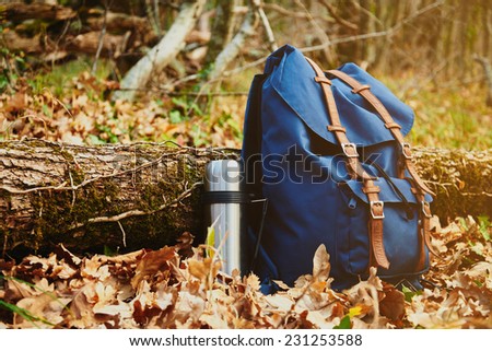 Thermos and backpack outdoors on autumn nature, hiking theme
