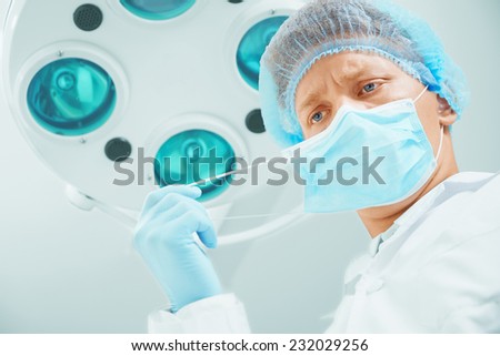 Young male surgeon doctor takes off his protective mask in operating room