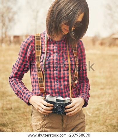 Tourist smiling young woman holding vintage old photo camera in spring outdoor