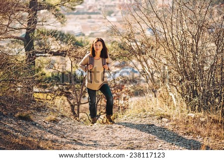 Young hiker woman with backpack trekking in autumn outdoor in highlands. Hiking and recreation theme