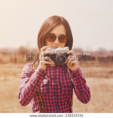 Traveler smiling hipster girl takes photographs with vintage old photo camera on nature