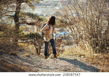 Young hiker woman with backpack looking back in autumn outdoor in highlands. Hiking and recreation theme