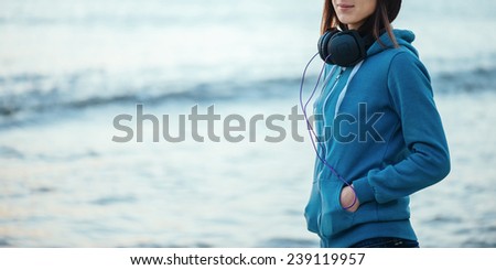 Girl with big headphones walking on beach near the sea