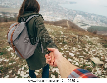 Hiker young woman holding man\'s hand and leading him on nature outdoor. Couple in love. Point of view shot. Focus on hands.