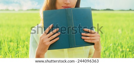 Unrecognizable woman holding a book in summer outdoor. Space for text on book