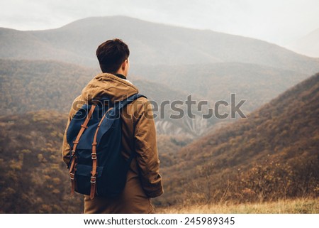Traveler man with backpack standing on hill and enjoying by scenic of mountains, rear view