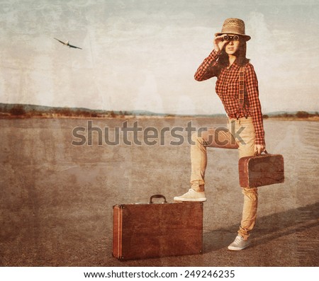 Tourist woman with vintage suitcase looking through binoculars on road, airplane in sky. Vintage image