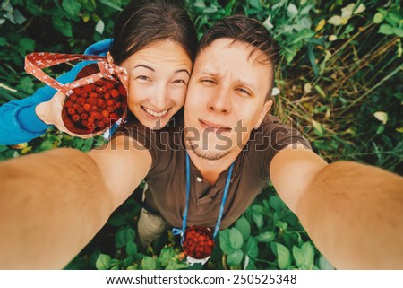 Happy young couple in love taking self-portrait in summer garden with raspberries