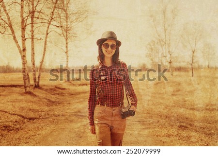 Traveler young woman with old photo camera on path outdoor. Image with vintage filter