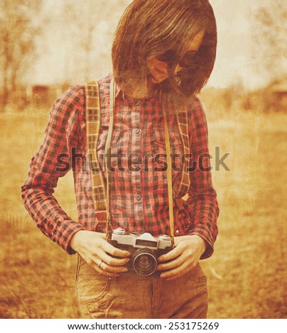 Tourist smiling young woman holding vintage old photo camera in spring outdoor. Vintage image