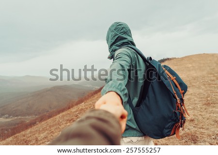 Traveler man holding woman\'s hand and leading her on nature outdoor. Focus on man. Point of view shot