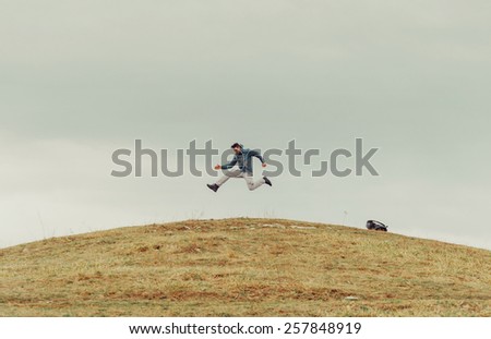 Happy traveler young man jumping on the mountain. Space for text in upper part of image