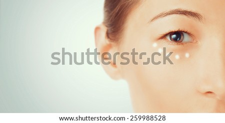 Portrait of young woman with cream around the eye, beauty and skincare concept