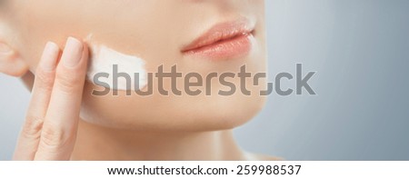 Young woman with smooth skin applying cream. Beauty and skincare concept