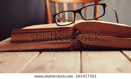 Old books and glasses  on a wooden table. Focus on glasses. Close-up