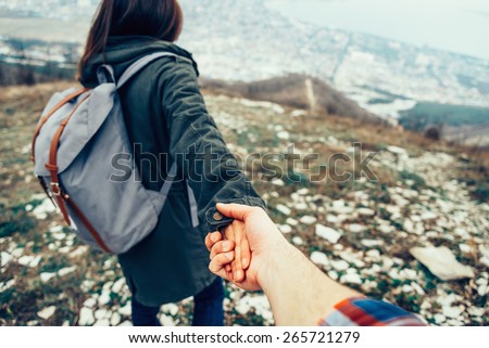 Hiker young woman holding man\'s hand and leading him on nature outdoor. Couple in love. Focus on hands. Image with instagram filter
