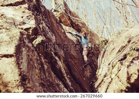 Active young woman climbing rock outdoor in summer