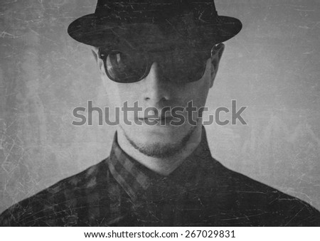 Portrait of serious man in sunglasses and hat. Image with old effect, textured image. Black and white image