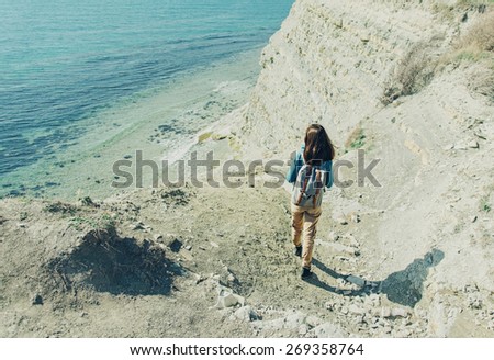 Young woman walking down to the sea in summer