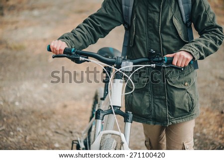 Hiker woman walking with bicycle in the forest, close-up