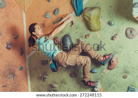 Climber sporty girl climbing on practice wall indoor