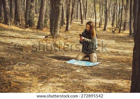 Hiker young woman searching direction with a compass and map in the forest