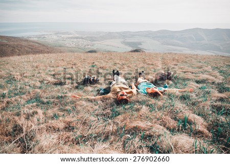 Couple in love lying on a mountain meadow above the sea in summer. Image with instagram filter