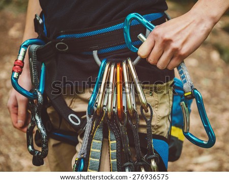 Close-up of female rock climber wearing safety harness with quickdraws and climbing equipment outdoor