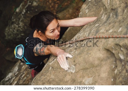 Beautiful young woman climbing on rock outdoor in summer, top view