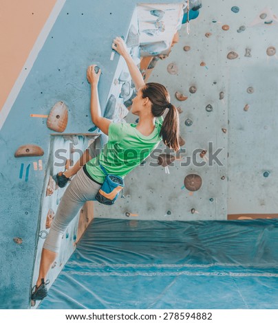 Beautiful young woman starts to climbing wall