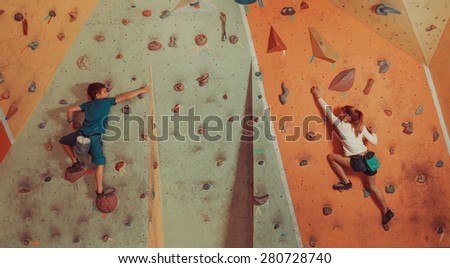 Sporty children climbing artificial boulder on practical wall in gym