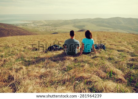 Loving couple sitting on mountain meadow and enjoying view of nature