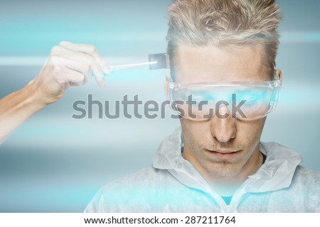 Human hand inserting a memory card in head of young man or robot, cyber space lighting, concept of modern technologies
