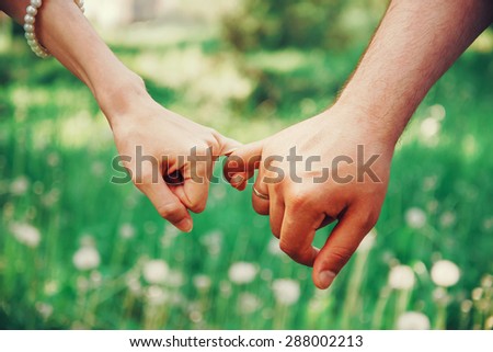 Married young loving couple holding hands each other in summer park, view of hands