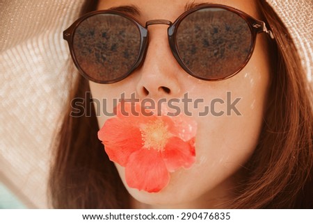 Portrait of young woman in sunglasses with red flower, concept of summer mood. Fashionable and beautiful summer girl