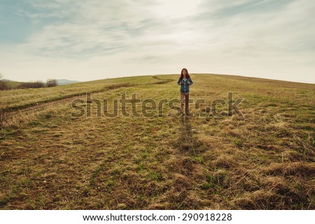 Beautiful hiker young woman with backpack walking on summer meadow, front view