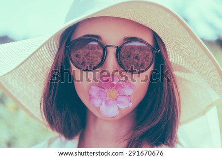 Portrait of young woman in sunglasses and hat with wide brim with flower, concept of summer mood. Fashionable and beautiful summer girl. Image with instagram color effect