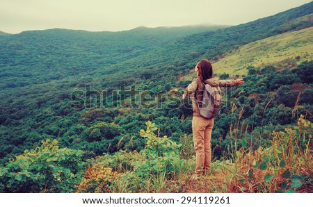 Freedom happy traveler woman standing with raised arms and enjoying a beautiful nature. Image with instagram color effect