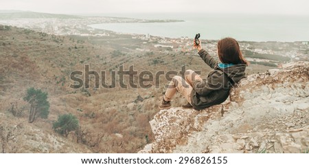 Hiker young woman sitting on peak of mountain and searching direction with a compass outdoor